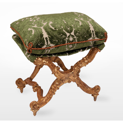 An Italian giltwood carved pliant, with a rectangular loose cushion seat in a green damask and trimming, above ‘X'-frame baluster supports, carved with scrolls, joined by shaped stretchers, on inward scrolled feet.